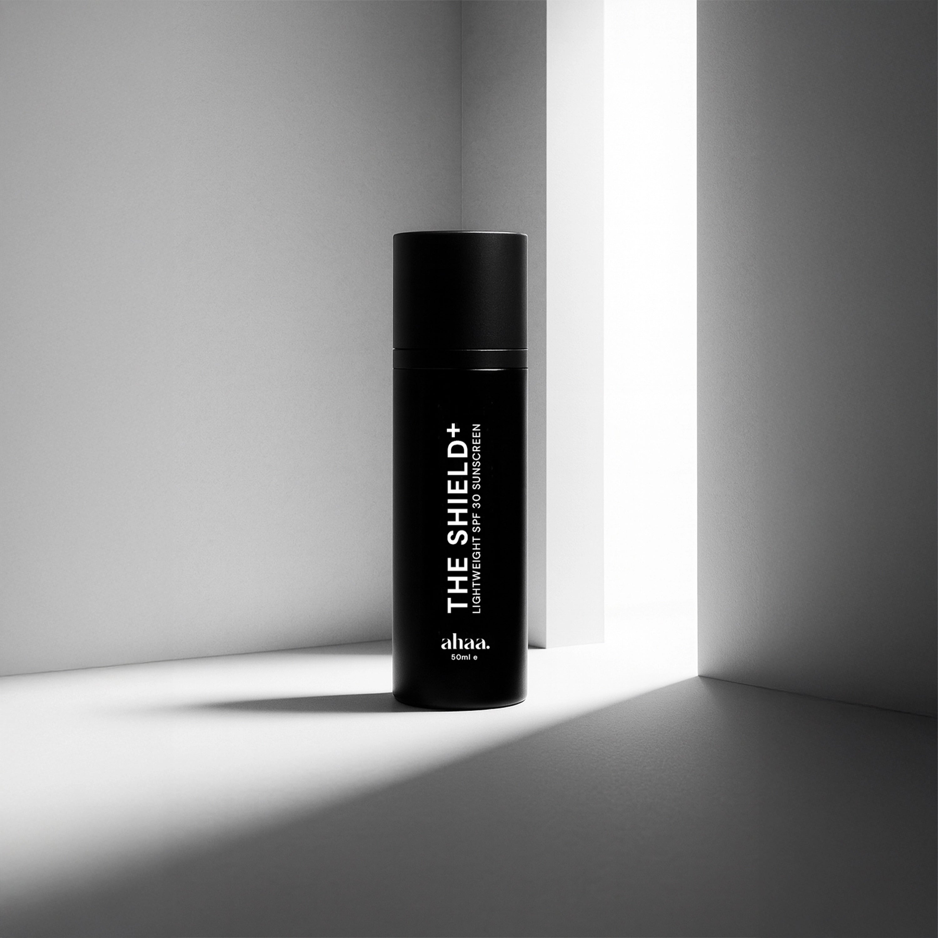 Black bottle labeled 'The Shield+' by Ahaa on a gray background